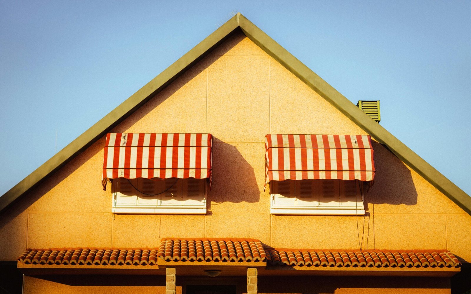 Close-up of a Spanish house in Madrid with red and white striped awnings under a clear sky.
